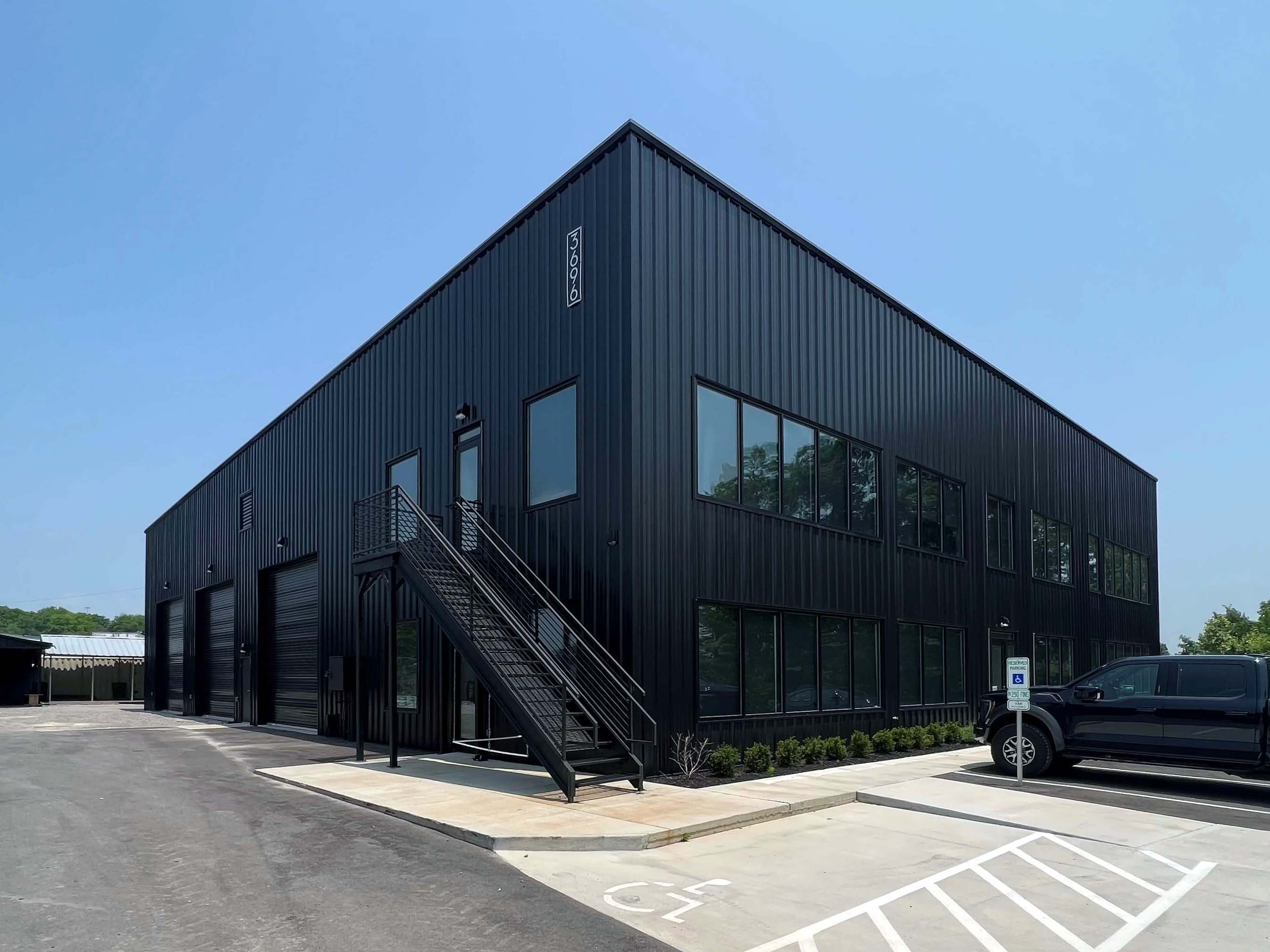 Authorized Equipment's dark two story metal shop with three large bay doors and offices on the right of the building.